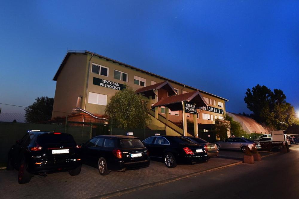 un gruppo di auto parcheggiate di fronte a un edificio di Meridiana Hotel a Novi Sad