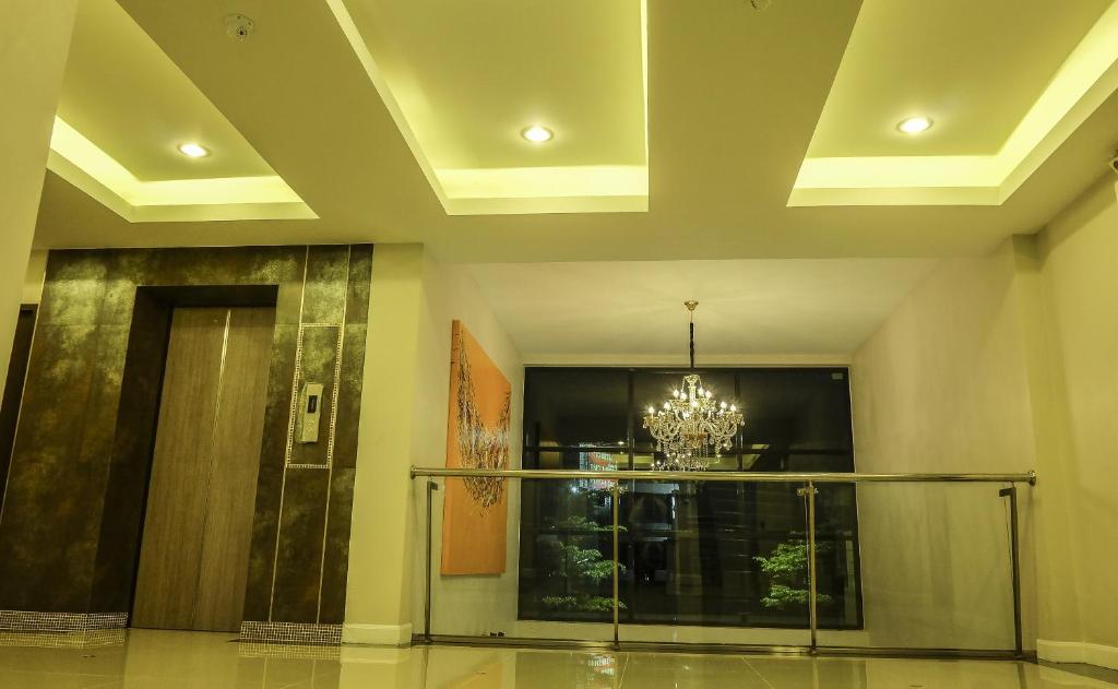 An upper-level lobby landing features a chandelier, elevator and glass railing.