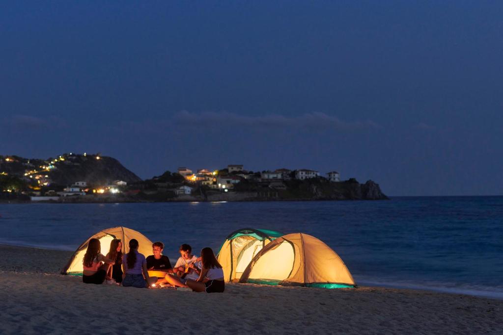 a group of people sitting around a campfire on the beach at Calaserena Resort in Geremèas