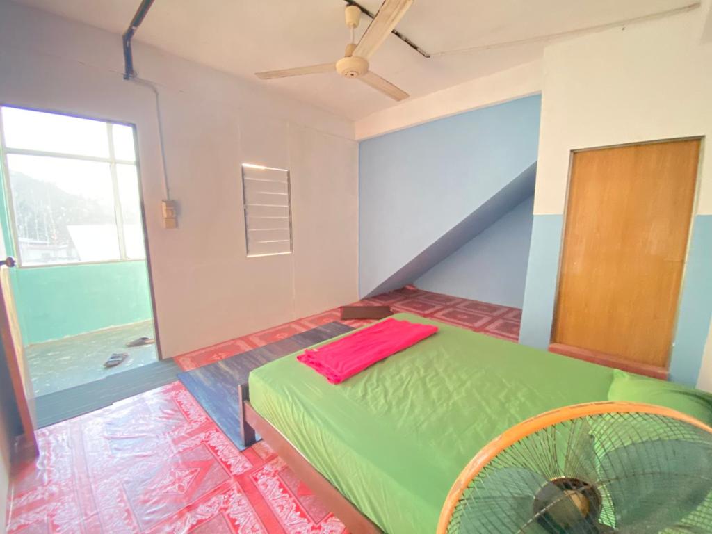 Schlafzimmer mit einem grünen Bett und einem Ventilator in der Unterkunft MY GUNUNG HOTEL BUDGET 