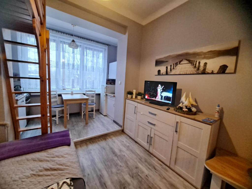 a room with a desk with a television and a dining room at Niezależny apartament przy Parku Zdrojowym in Kudowa-Zdrój