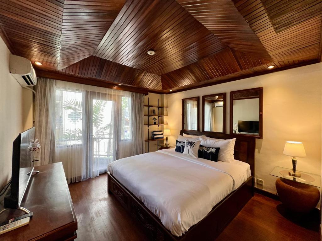 1 dormitorio con 1 cama grande y techo de madera en Galayanee’s Resort Apartment, en Seminyak