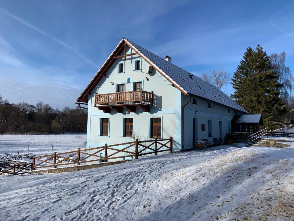 a white house with a balcony on top of it in the snow at Penzion Stanský Mlýn in Hlinsko