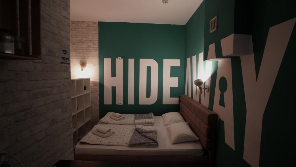 a small bedroom with a bed with a green wall at Hideaway Rooms & Apartments Sarajevo in Sarajevo