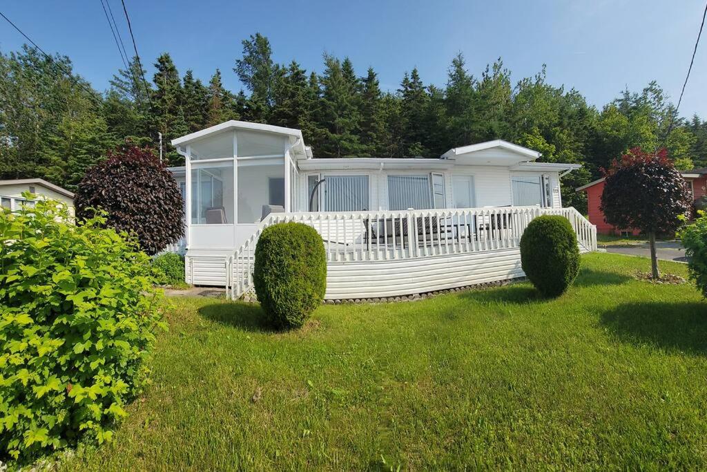 une maison blanche dans une cour avec des buissons dans l'établissement Maison Miramar à 5 min de la Baie, à Sainte-Luce-sur-Mer