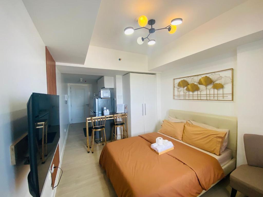 a bedroom with a bed and a flat screen tv at AzureNorth 17F Mt Arayat View in Del Rosario