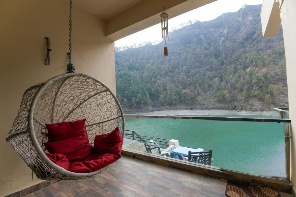a hanging chair with red pillows in front of a large window at Allure lake front in Nainital
