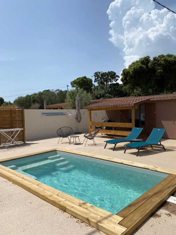 une piscine avec des chaises bleues et une maison dans l'établissement Petit chalet d’été avec piscine privée chauffée, à Bonifacio