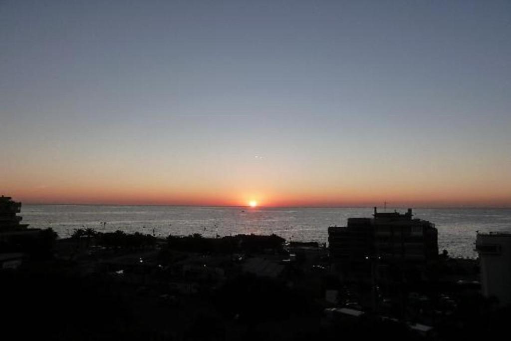a sunset over the ocean with a city at Venere B&B in Catania