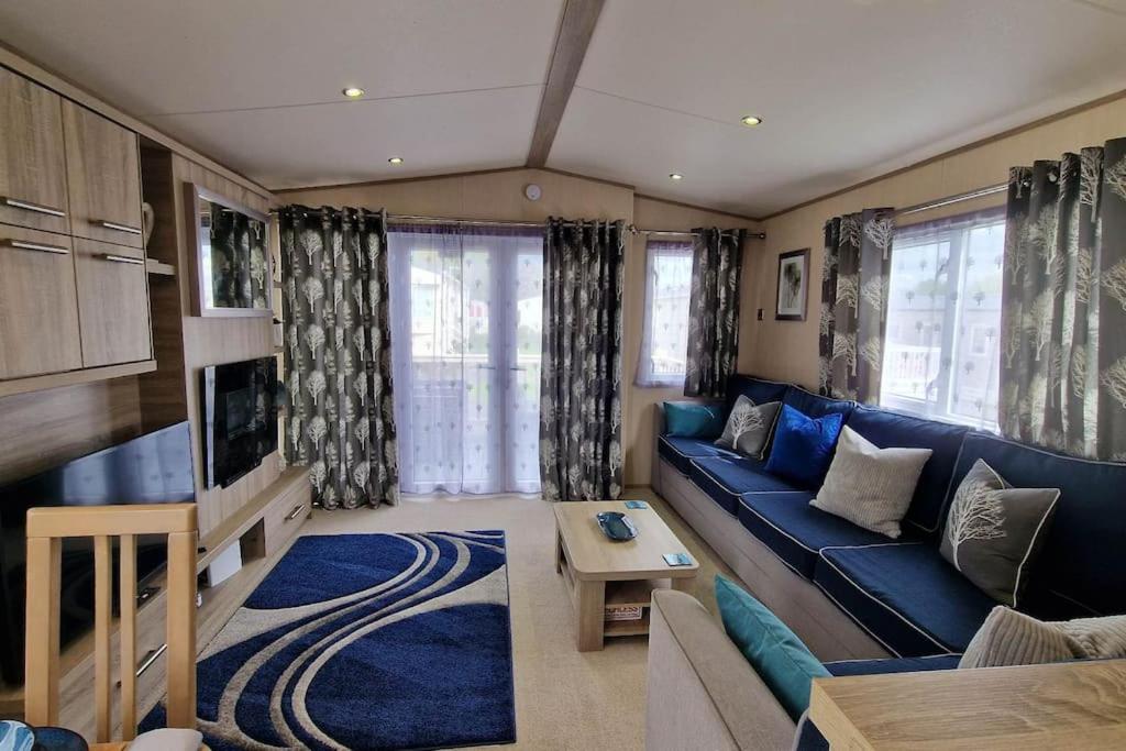 a living room with a blue couch and a tv at Contemporary home at Tarka Holiday Park Barnstaple in Barnstaple