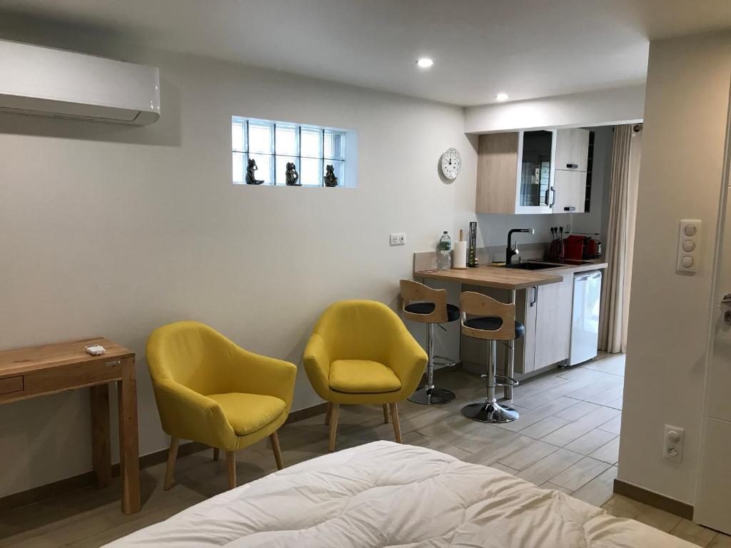 Cet appartement comprend une chambre avec deux chaises jaunes et une cuisine. dans l'établissement Studio neuf de 24m², à Brive-la-Gaillarde