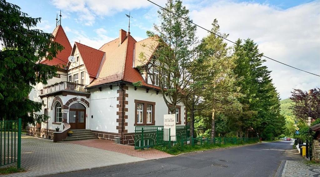 uma casa branca com um telhado vermelho numa rua em Willa Pałacyk em Świeradów-Zdrój