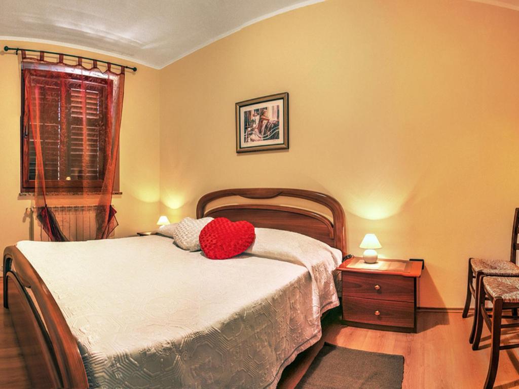 a bedroom with a bed with a red pillow on it at Apartment Agroturizam Radešić in Buje