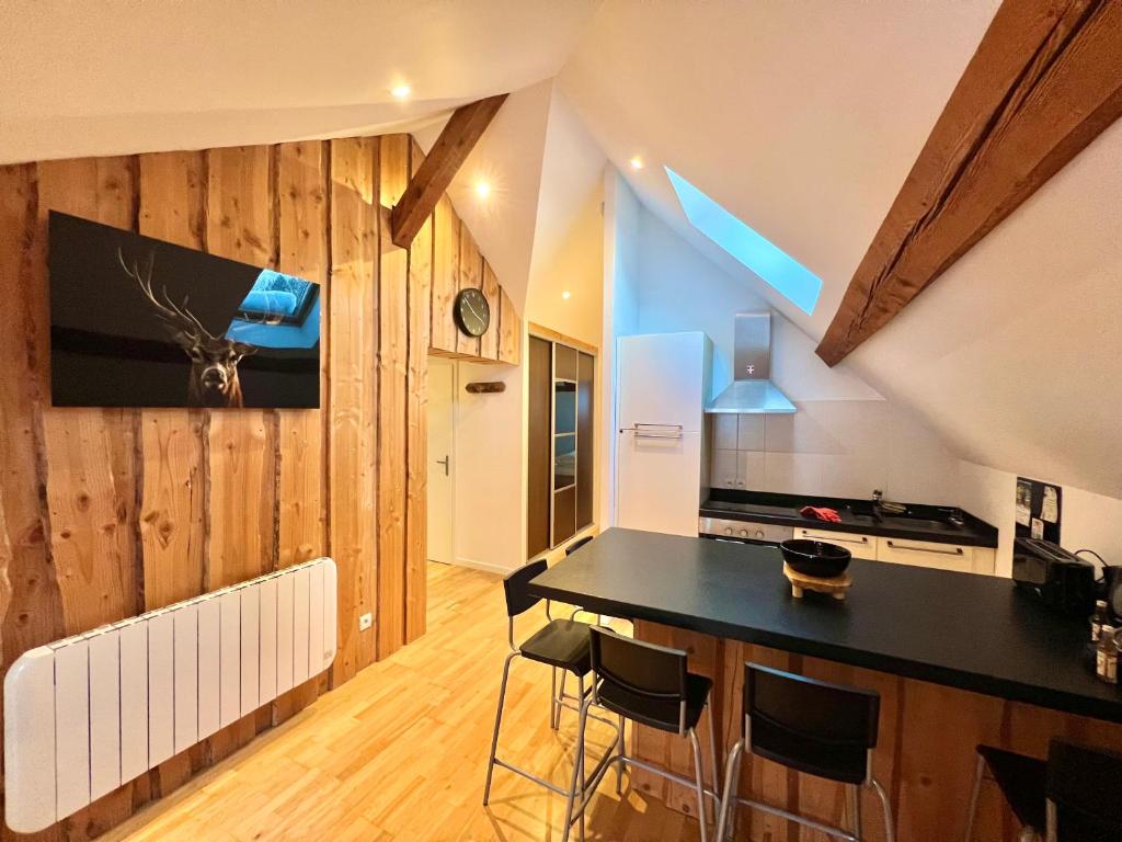 - une cuisine avec un comptoir noir et des murs en bois dans l'établissement La perle Bressaude avec balcon et magnifique vue, à La Bresse