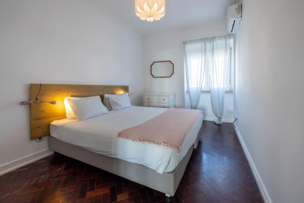 um quarto com uma grande cama branca e uma janela em Casa do Largo-vista sobre Lisboa em Lisboa
