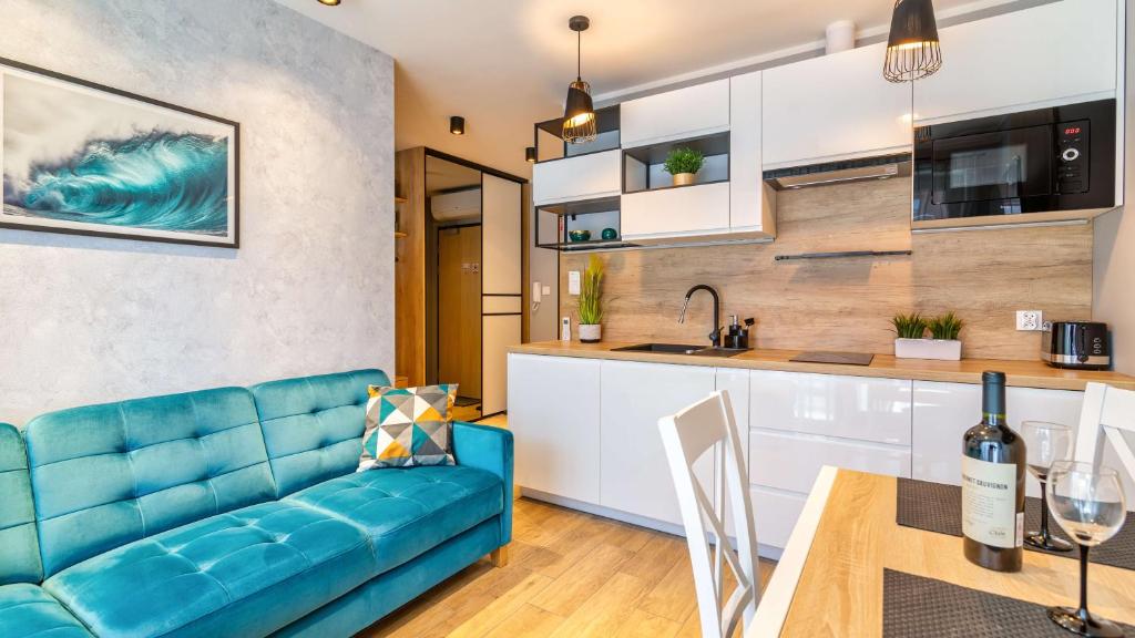 a living room with a blue couch and a kitchen at STEGNA PARK B Apartamenty PIAMOLA in Stegna