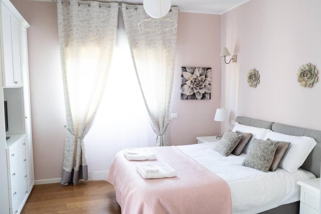 - une chambre blanche avec un grand lit et une couverture rose dans l'établissement Casa Ludmila, à Corsico