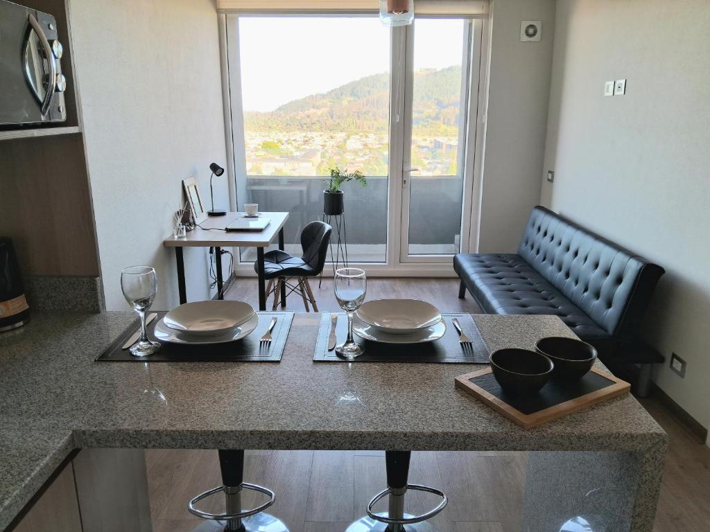 een keuken met een tafel met wijnglazen en een woonkamer bij Departamento central con estacionamiento in Temuco