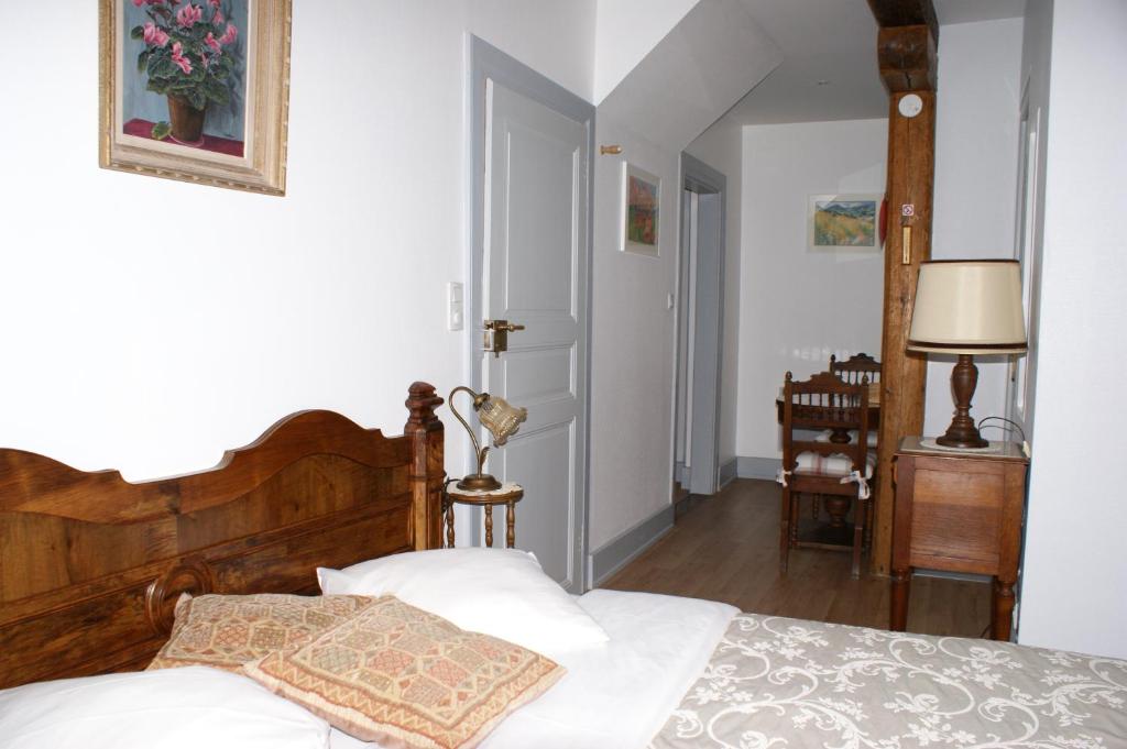 ein Schlafzimmer mit einem Bett mit einem Kopfteil aus Holz in der Unterkunft Location "Charme" in Riquewihr