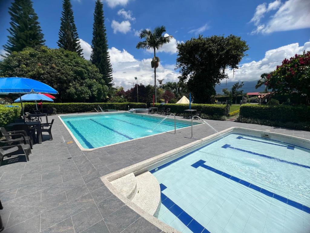 una grande piscina con patio e ombrellone di Villa Alejandra Del Quindio a Calarcá