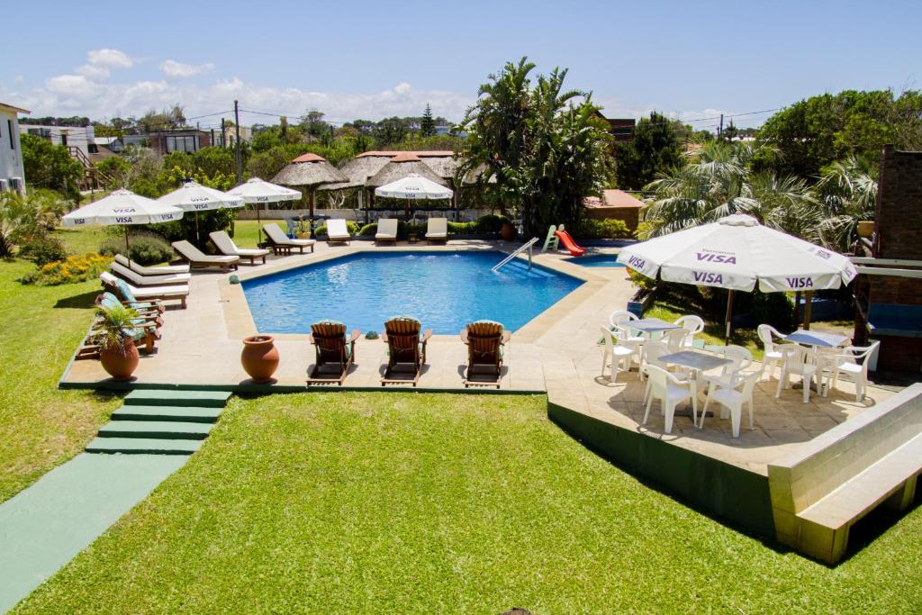 uma piscina de resort com cadeiras, mesas e guarda-sóis em Hotel de la Torre em La Paloma