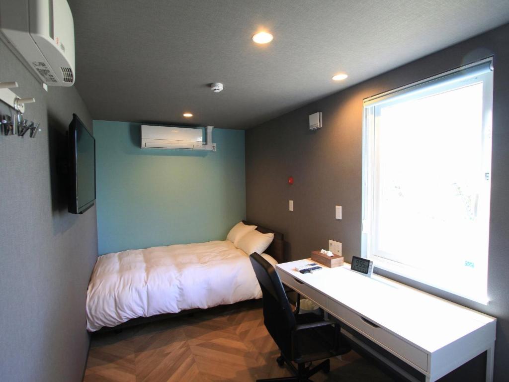 a bedroom with a bed and a desk with a desk at HOTEL KUTEKUN - Vacation STAY 31431v in Naka-shibetsu