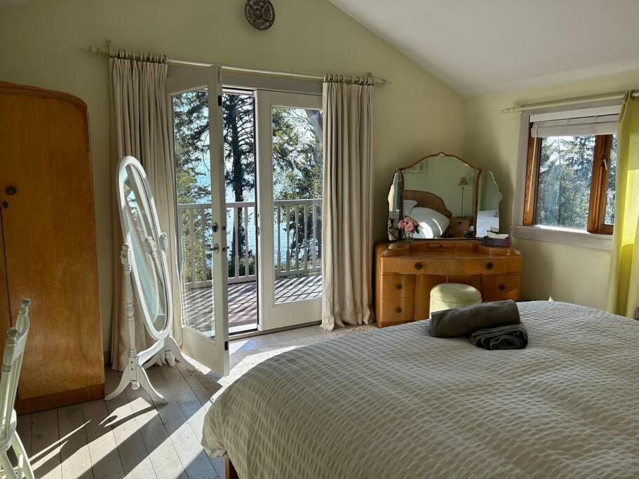 Schlafzimmer mit einem Bett, einem Spiegel und einem Fenster in der Unterkunft French Beach House Shirley BC in Shirley