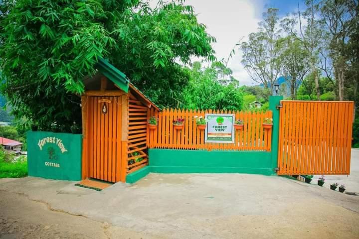 een oranje hek met een bord naast een boom bij Thalagala Oya Resort & Restaurant in Nuwara Eliya