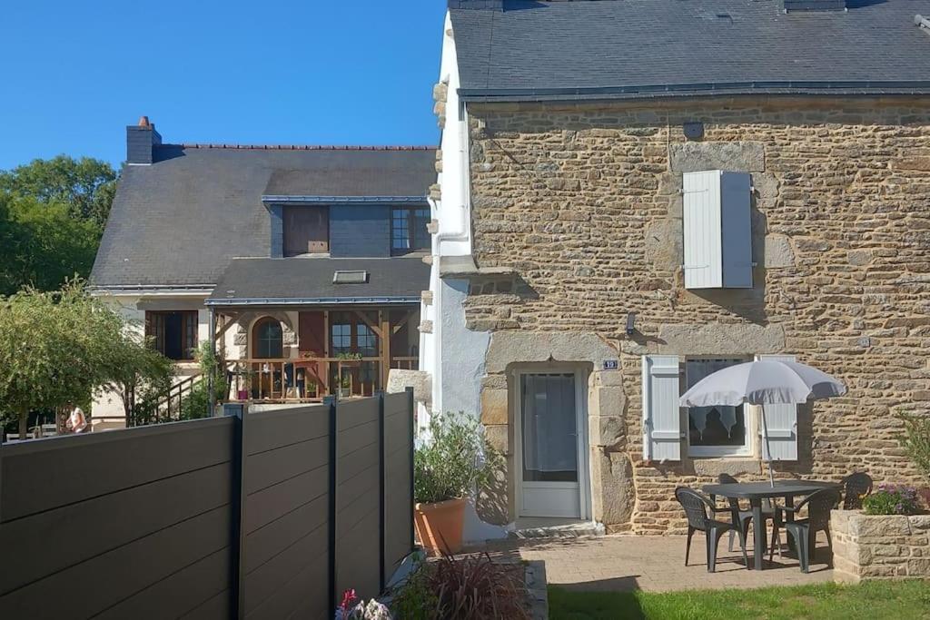 a house with a table and an umbrella in the yard at Maison de campagne au calme in Molac