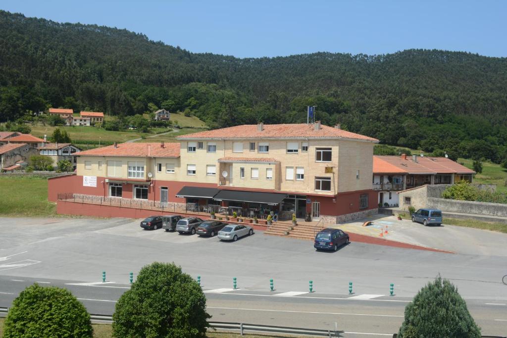 un gran edificio con coches estacionados en un estacionamiento en Hostal Baviera, en Pesués