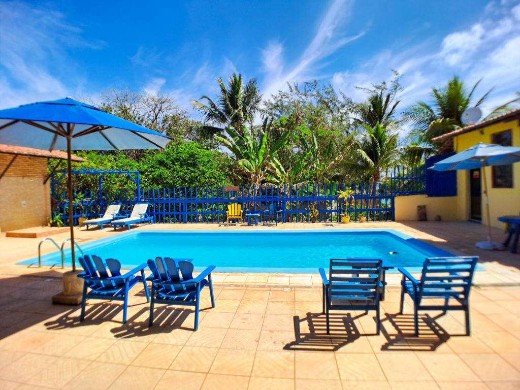 a swimming pool with blue chairs and umbrellas at Pousada Praia do Amor in Pipa