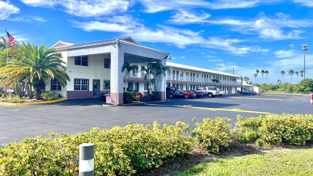 a hotel building with a parking lot and palm trees at Flamingo Motel in Okeechobee