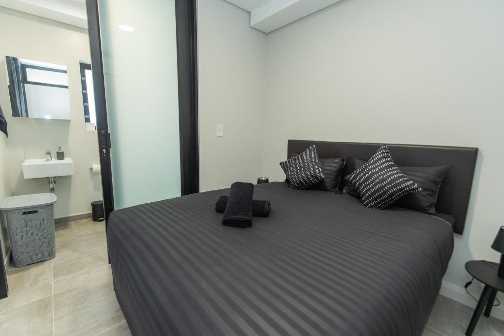 a bedroom with a large bed with black pillows at Bella Cabana Luxury Apartment in Summerstrand
