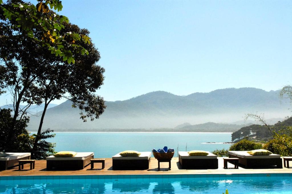 a pool with lounge chairs and a view of the water at Pousada Picinguaba in Ubatuba