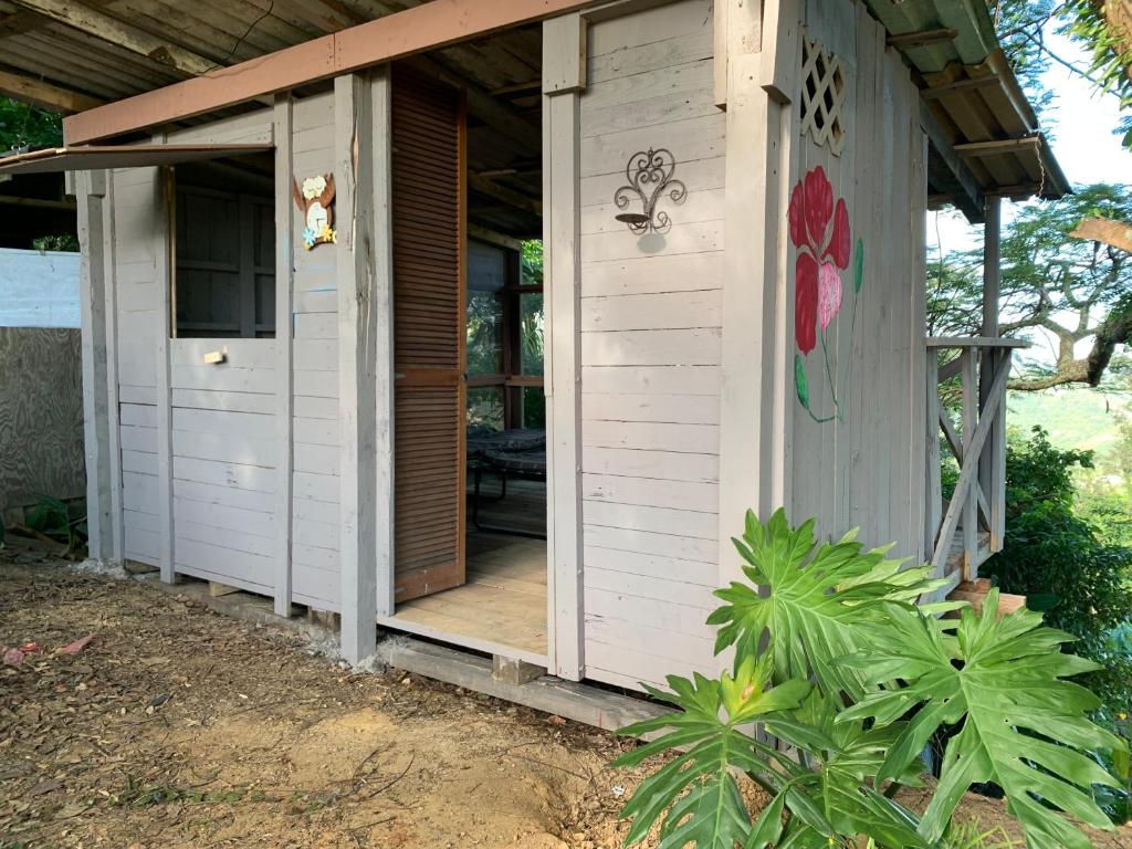 a small white house with a porch and a door at Camping para dos - a escoger segun disponibilidad de caseta o cabaña in Caguas