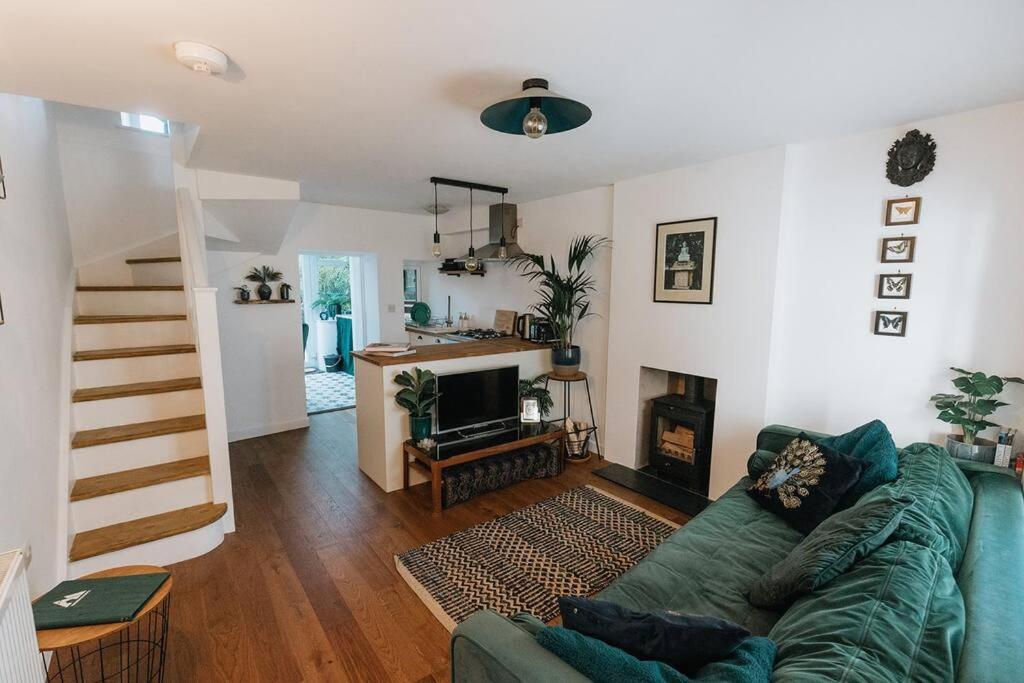 a living room with a green couch and a fireplace at Unique Cottage in the heart of Ulverston in Ulverston