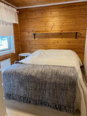 ein Schlafzimmer mit einem Bett mit einer Holzwand in der Unterkunft Levi Piippo 2 in Kittilä