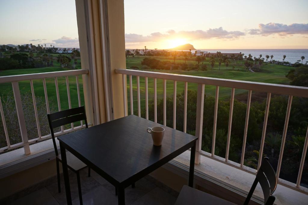 a table and chairs on a balcony with a view of the ocean at Golf del Sur Apartment - magnificent panorama of the ocean, el Teide, and Montaña Roja in San Miguel de Abona