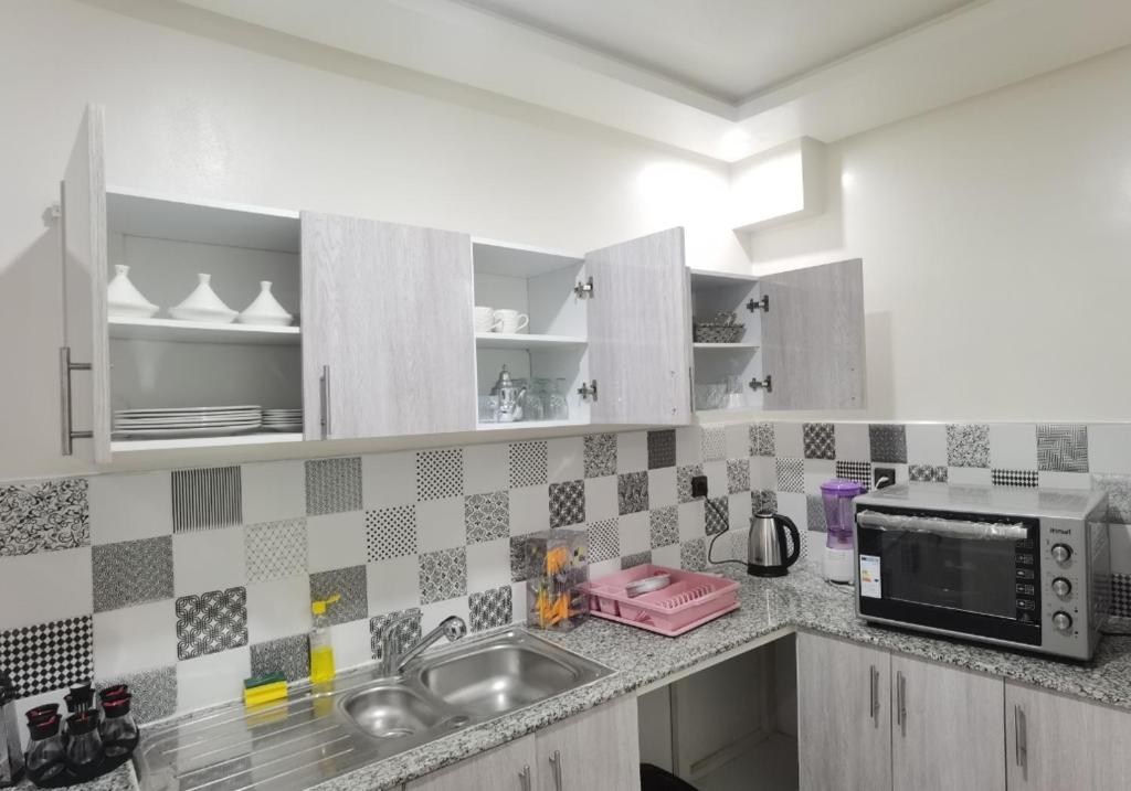 a kitchen with a sink and a microwave at شقق مفروسة المشور in Laayoune