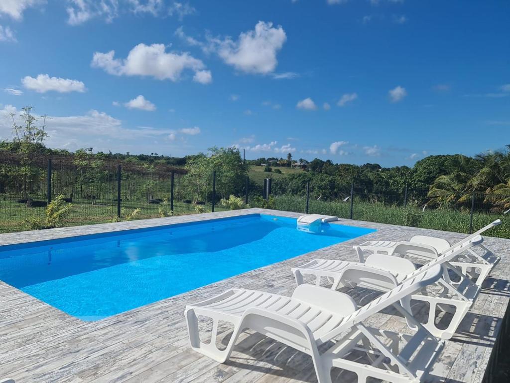 a pool with lounge chairs and a swimming pool at Maison Laurencia - Appartement au rez-de-chaussée avec jardin in Sainte-Anne
