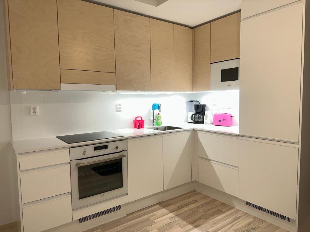 奧盧的住宿－Ade 1，厨房配有白色橱柜和粉色家电