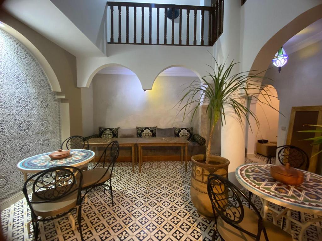 un soggiorno con tavoli, sedie e divano di Riad D’AR GANne by Carole a Essaouira