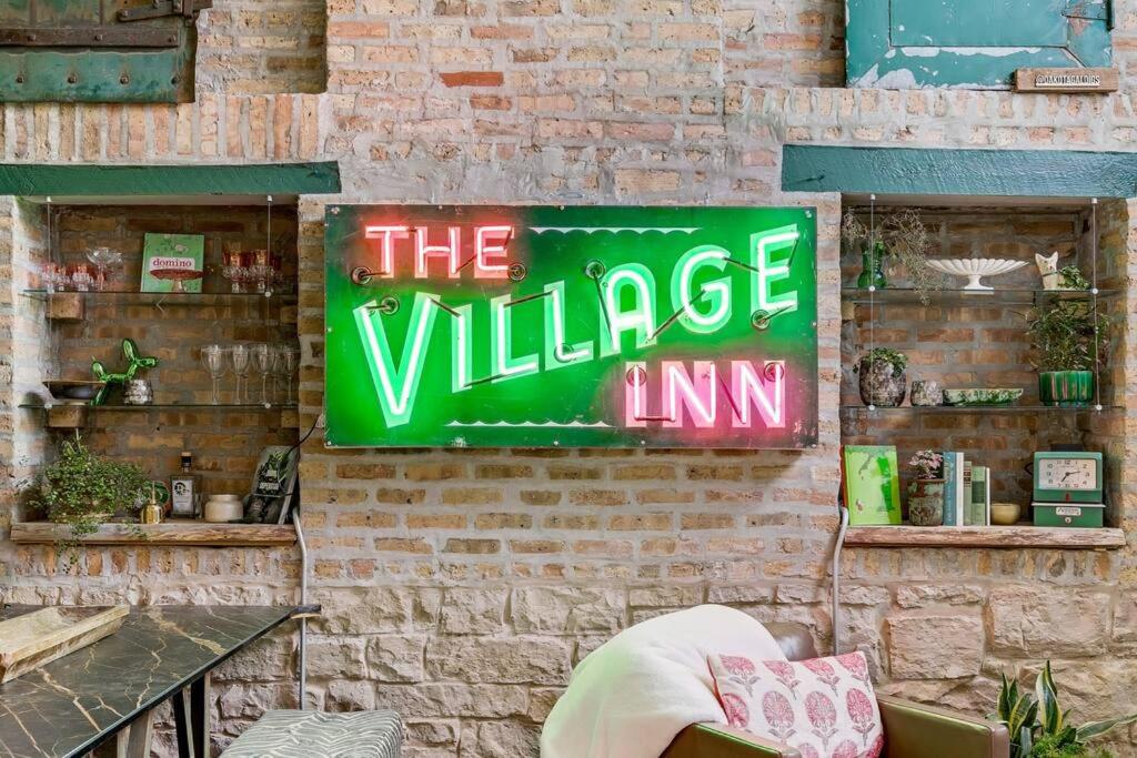ein Schild an einer Ziegelmauer, das den Dorfgasthof liest in der Unterkunft The Village Inn by Dakota Gal Digs in Chicago