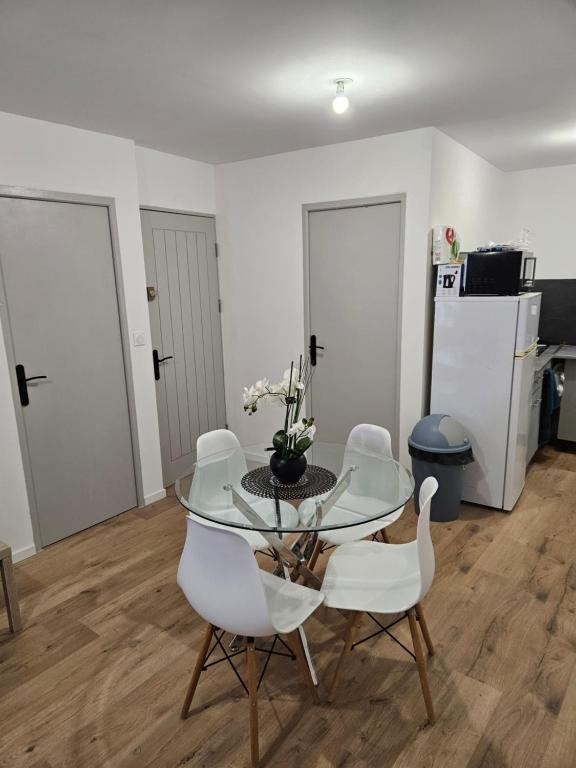 une salle à manger avec une table en verre et des chaises blanches dans l'établissement T2 chaleureux, calme et entièrement rénové., à Béziers