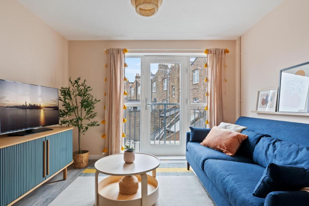 a living room with a blue couch and a large window at Stylish 2 Bed Flat in Vibrant East London in London