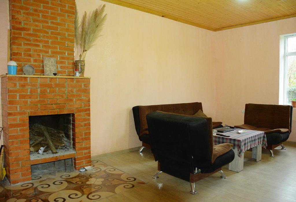 een woonkamer met stoelen en een stenen open haard bij Guesthouse Lasha in Khoni