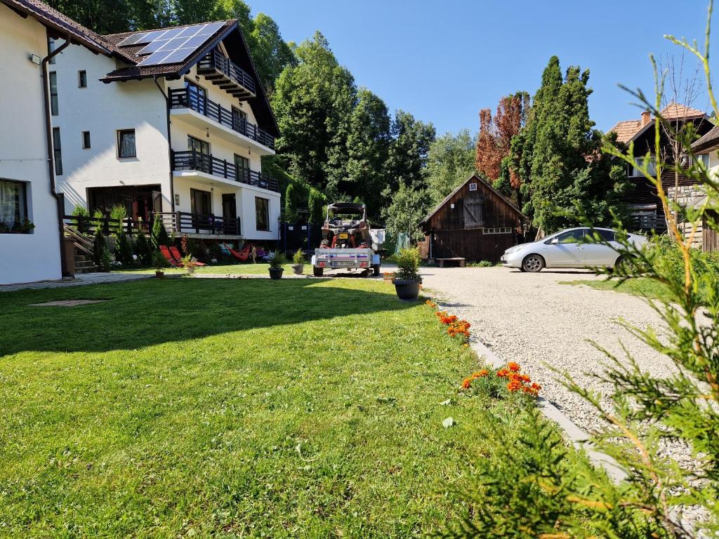 een tuin met een huis en een auto op een oprit bij Casa Maria Moieciu de Sus in Moieciu de Sus