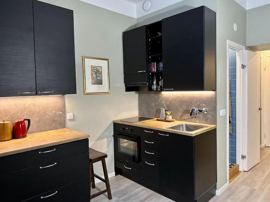 a kitchen with black cabinets and a sink at Boutique Studio in the city in Helsinki