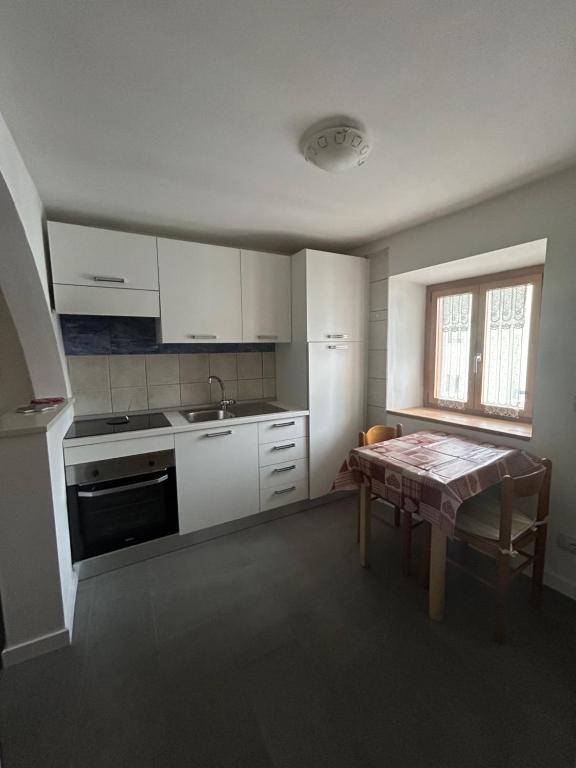 a kitchen with white cabinets and a table and a window at Appartamento Travai in Predazzo