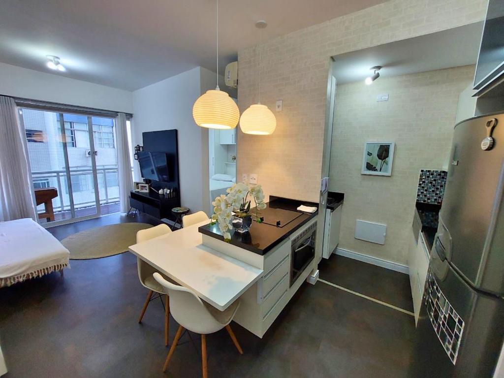 a kitchen and living room with a table and a refrigerator at Book Santos - Unlimited 716 - Vista Mar Lateral in São Vicente